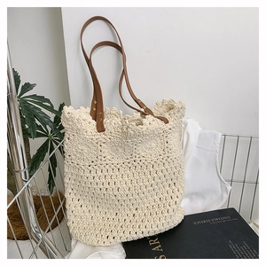 Detail of hand-woven off-white tote bag with brown leather straps and gold rivets
