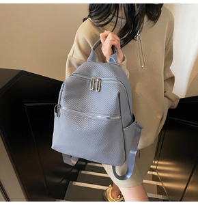 Detail of blue-purple textured backpack showing fine woven pattern and silver zippers