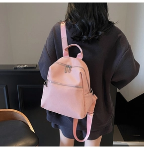 Rear view of a pink minimalist water-resistant backpack with wide straps on a model