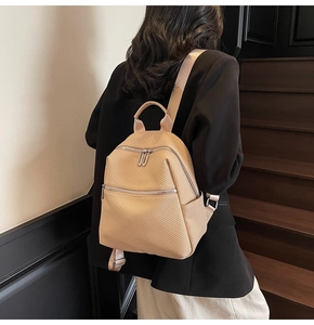 Detail of beige woven texture backpack with dual zipper and hidden front pocket