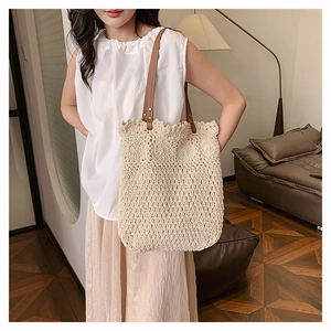 Close-up of beige woven tote bag showing crochet patterns and brown leather straps