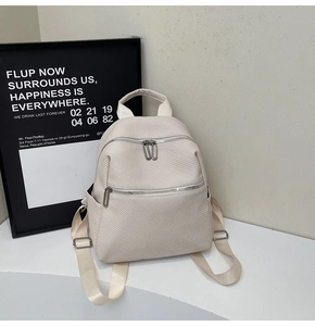 Detail of cream backpack with woven texture, multiple zipper pockets and side pockets