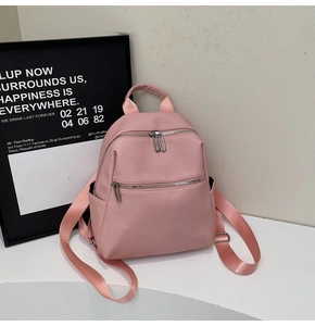 Detailed close-up of light pink backpack with honeycomb textured fabric and silver zippers