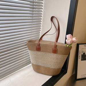 Striped straw tote bag with brown leather straps shown against a sunlit window
