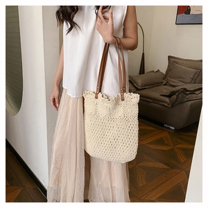 Detail of hand-woven crochet tote bag featuring durable brown leather straps and metal rivets