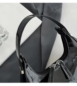 Détail du sac croissant en cuir verni noir brillant avec double fermeture et poignée