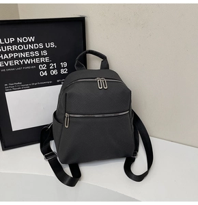 Detail view of large charcoal textured fabric backpack with silver zippers and side pockets