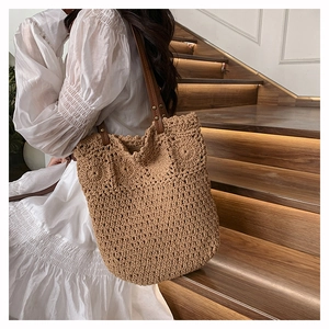 Macro view of woven tote bag with crochet floral patterns and brown leather straps