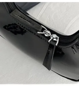 Détails des fermetures à glissière en métal sur un sac en cuir verni noir brillant