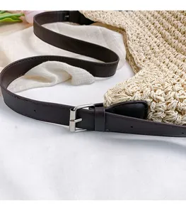 Detailed close-up of the silver buckle and woven straw texture on a white tote bag