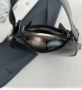 Vue intérieure du sac hobo en cuir verni noir avec espace pour téléphone et maquillage