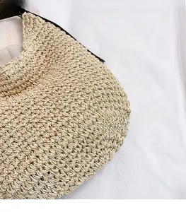 Close-up of beige woven shoulder bag showing handmade texture and brown leather strap
