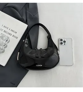 Gros plan du sac croissant en cuir verni noir avec double fermeture éclair et boucles argent