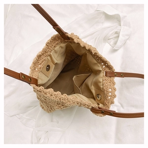 Detailed top view of a woven shoulder bag interior with magnetic closure and brown leather strap