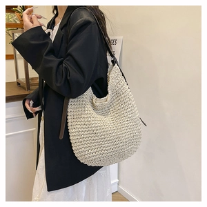 Detail of the woven texture and contrast dark leather strap on the beige hobo shoulder bag