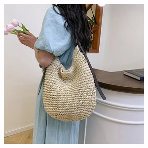 Detail of hand-woven beige bucket bag with brown adjustable leather strap and texture
