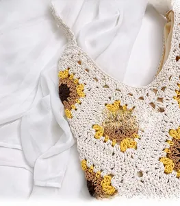 Détail du sac en paille crocheté avec motif tournesol jaune et texture tricotée