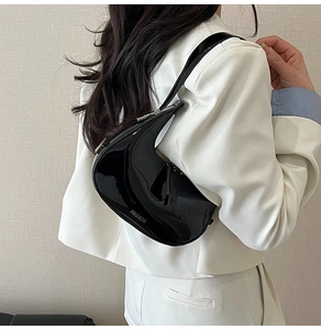 Détail du sac croissant noir brillant avec quincaillerie argentée et lettrage