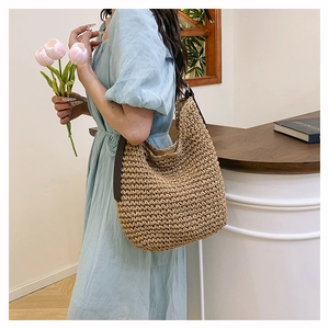 Detail of large woven shoulder bag with brown leather strap and high-capacity hobo design