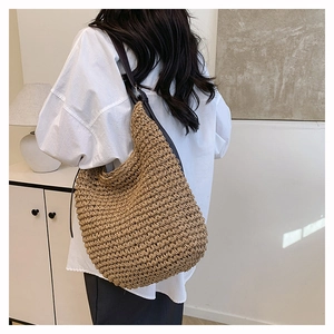 Close-up of a handwoven straw shoulder bag featuring a brown leather strap and tight texture