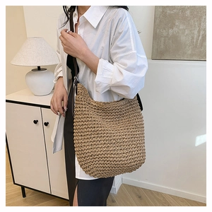 Close-up of the woven texture and leather strap on this large summer straw shoulder bag