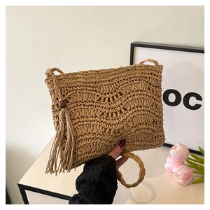 Detail of bohemian straw woven crossbody bag featuring wood bead and long fringe tassel