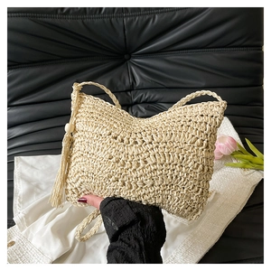 Detailed macro view of beige woven crossbody bag with long tassels and raffia texture