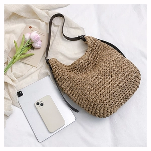 Macro detail of the natural woven texture and brown leather strap on the large hobo bag