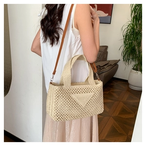 Detail of hollow woven shoulder bag with brown leather strap and woven triangle patch