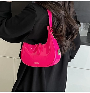 Détail du sac demi-lune en cuir verni fuchsia avec lettrage argenté et bandoulière