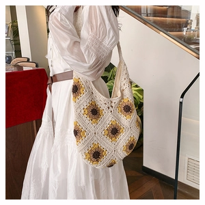 Détail du sac hobo en paille tissé main avec motif tournesol jaune et texture crème