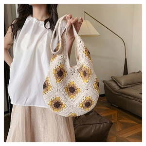Détail d'un sac cabas en paille tissé main avec motifs de tournesols au crochet