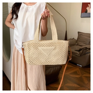 Detail of a beige woven tote bag featuring a triangle texture and slim brown shoulder strap