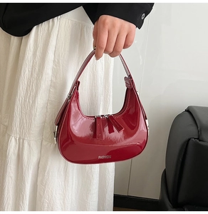 Détail du sac croissant rouge en cuir verni brillant avec lettrage métallique mode