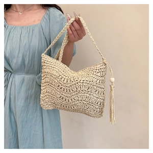 Detail of hand-woven beige straw bag with long tassels and decorative wooden beads