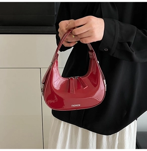 Détail du sac croissant en cuir verni rouge avec double fermeture éclair et lettrage fashion