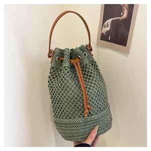 Détail d'un sac seau au crochet vert sauge avec bandoulière en cuir marron et cordon serrage