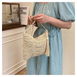 Detail of beige hand-woven crochet bag with tassels and thin shoulder strap on model