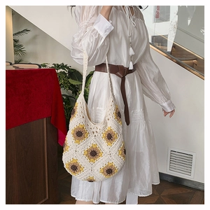 Détail du sac en paille au crochet bohème avec motif tournesol porté par un mannequin