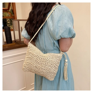Detail of hand-woven straw crossbody bag with fringe tassels and wooden bead accents
