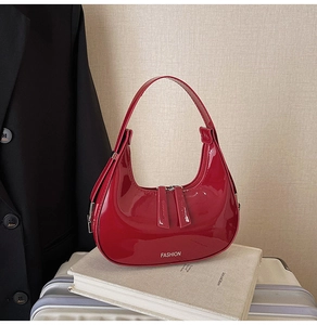 Détail du sac hobo en cuir verni rouge avec texte de mode et double fermeture éclair