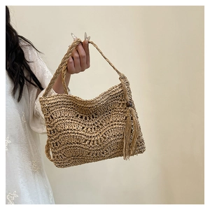 Detail of woven straw handbag featuring hollow wave pattern and side tassel with wood bead
