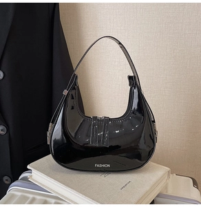 Détail du sac croissant en cuir verni noir avec finition brillante et lettrage fashion