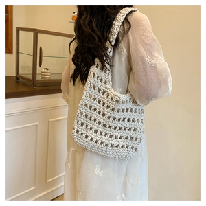 Detail of a white crochet woven shoulder bag showing hollow grid pattern and texture