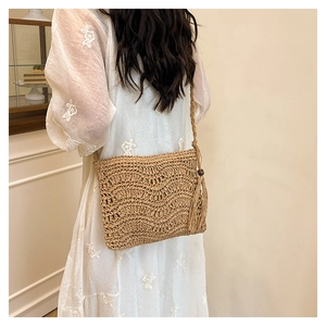 Detail of woven straw shoulder bag with wave patterns, tassels and wooden beads