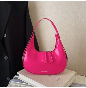 Gros plan d'un sac hobo en cuir verni rose vif avec texture brillante et logo de mode