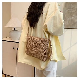 Detail of woven straw shoulder bag with bohemian fringe and hollow wave pattern