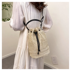 Détail du sac seau tissé avec motif ajouré et bandoulière en cuir noir chic