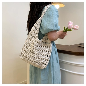 Shoulder view of a cream hand-woven crochet tote bag with hollow mesh pattern