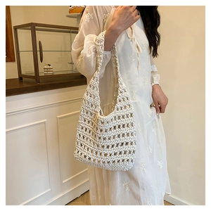 Detailed view of cream-colored woven tote bag featuring an intricate openwork knit pattern